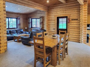 L’intérieur d’une cabane en rondins, avec une table à manger, des chaises, un canapé et une cheminée.