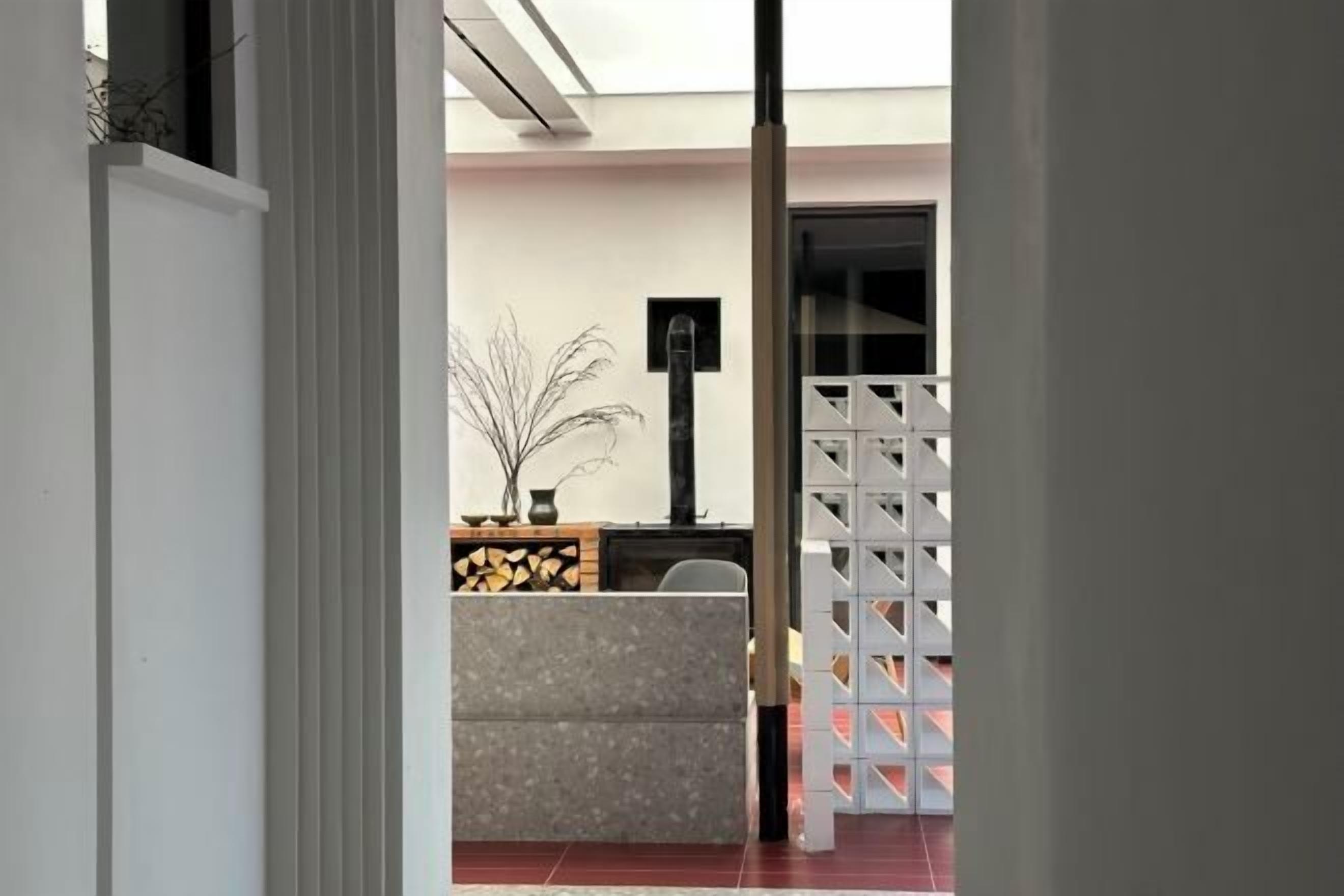 A hallway with a reception desk, a plant, a fireplace, and a white partition.