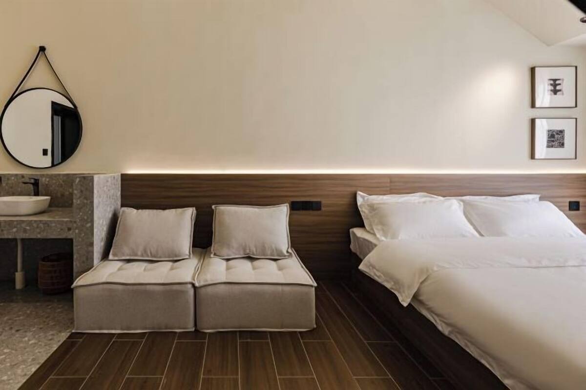 A hotel room with a bed, two bedside tables, a mirror, and a sink.