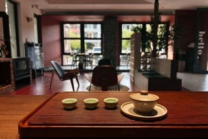 A table with a teapot and four cups in a modern interior with large windows and a view of the street.