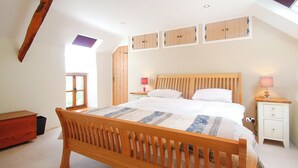 Een slaapkamer met een houten bed, dakraam, kledingkast en nachtkastje met lamp.