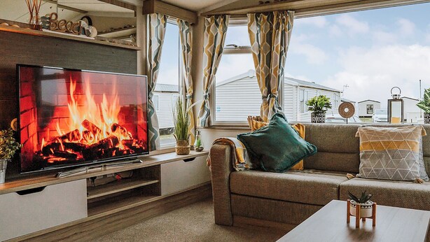 A cozy living room with a fireplace, a flat-screen TV, a sofa, and a coffee table. - A perfect family coastal break in the heart of Ayrshire. (Ayr)