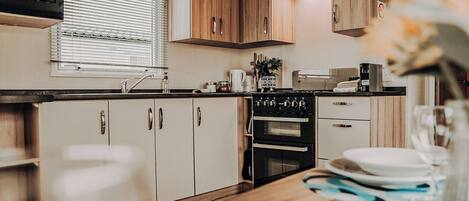 Una cocina compacta con armarios de madera, un microondas, una estufa y un lavamanos.