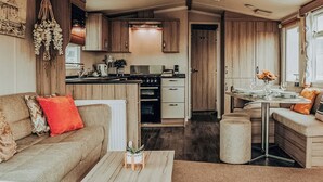 A compact RV interior with a kitchenette, a dining area, and a living space with a sofa and coffee table. - A perfect family coastal break in the heart of Ayrshire. (Ayr)
