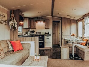 Ein kompaktes Wohnmobil-Interieur mit Küchenzeile, Essbereich und Wohnraum mit Sofa und Couchtisch.