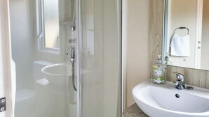 Une salle de bain moderne avec une douche à parois de verre, un lavabo blanc et un miroir.