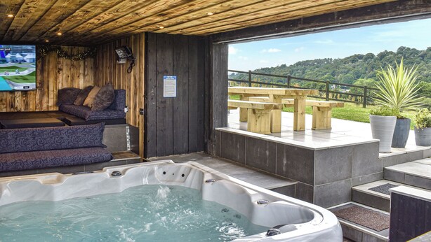 A wooden interior with a hot tub, seating area, and a view of a hillside. - 5 bedroom accommodation in Rudyard Lake (Rudyard Lake)