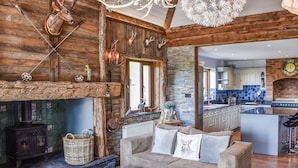 A rustic interior with a fireplace, wooden beams, a woven basket, a sofa, and a kitchen area. - This bespoke designer property has the wow factor in abundance. (Rudyard Lake)