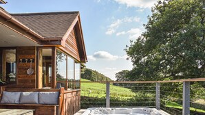 A wooden cabin with a hot tub on a deck, overlooking a green landscape. - This bespoke designer property has the wow factor in abundance. (Rudyard Lake)