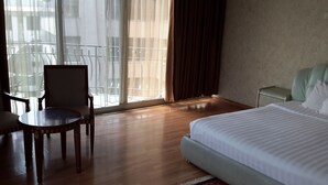 Ein Hotelzimmer mit einem Bett, einem Sessel, einem kleinen Tisch und einem Fenster mit Vorhängen.