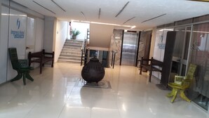 Eine Hotelhalle mit einer großen Vase, einer Treppe und Sitzbereichen.