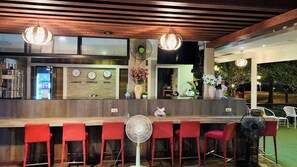 A bar area with red chairs, a wooden ceiling, and a clock displaying time in London, Bangkok, and Seoul. - Tamnan Resort Pattaya (Pattaya)