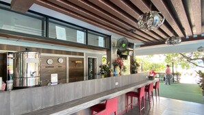 Un espace bar moderne doté d’un distributeur en acier inoxydable, d’éléments décoratifs en bois et de tabourets de bar rouges.