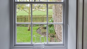 A window with a view of a grassy area, a wooden fence, and a wicker wall. - Cuthbert House - UK7026 (Longframlington, near Rothbury)