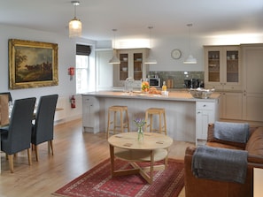 Une cuisine moderne avec un îlot central, des chaises en bois, une table à manger et un tapis rouge.
