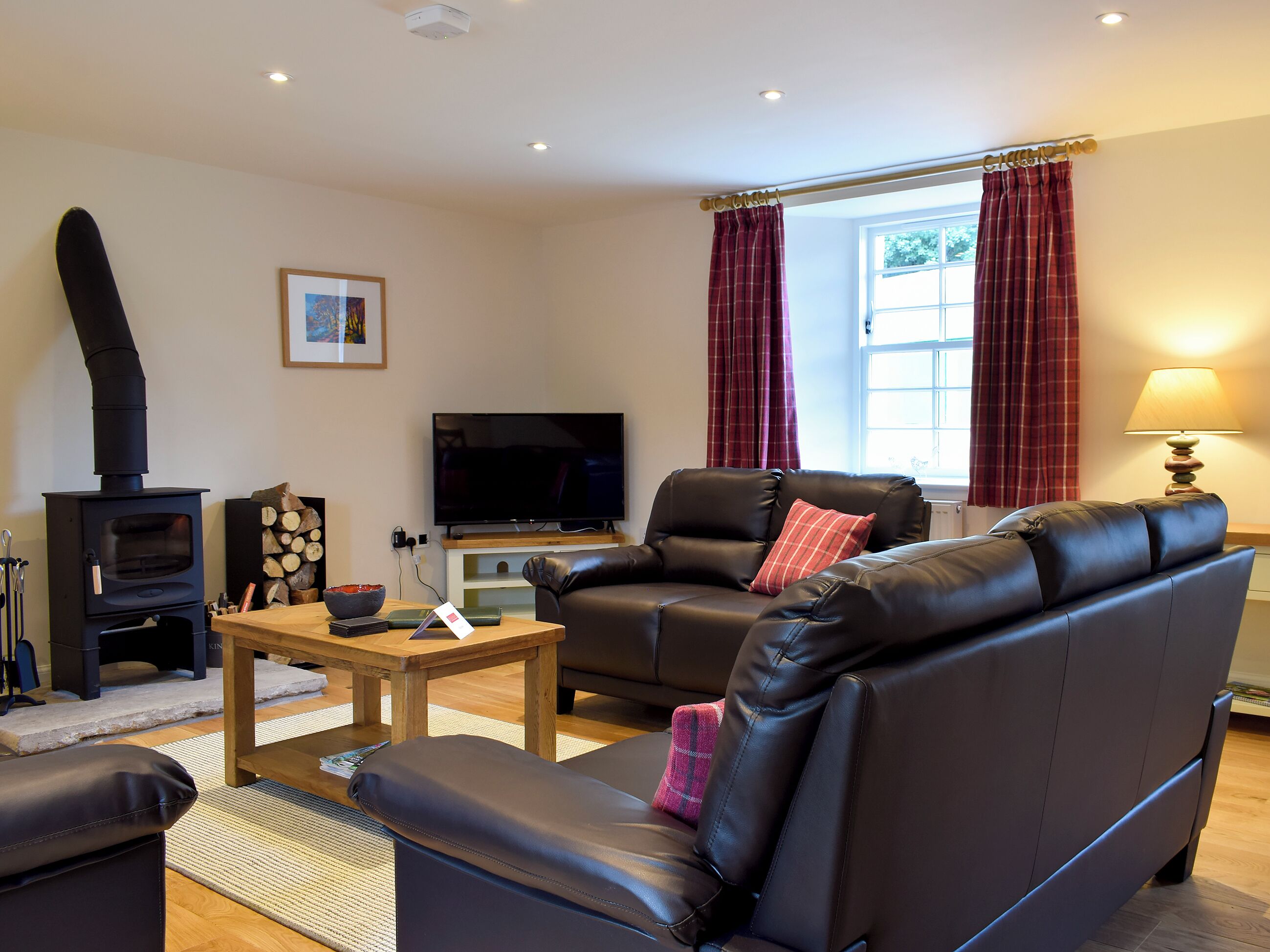 A living room with a sofa, a television, a fireplace, and a window with curtains.