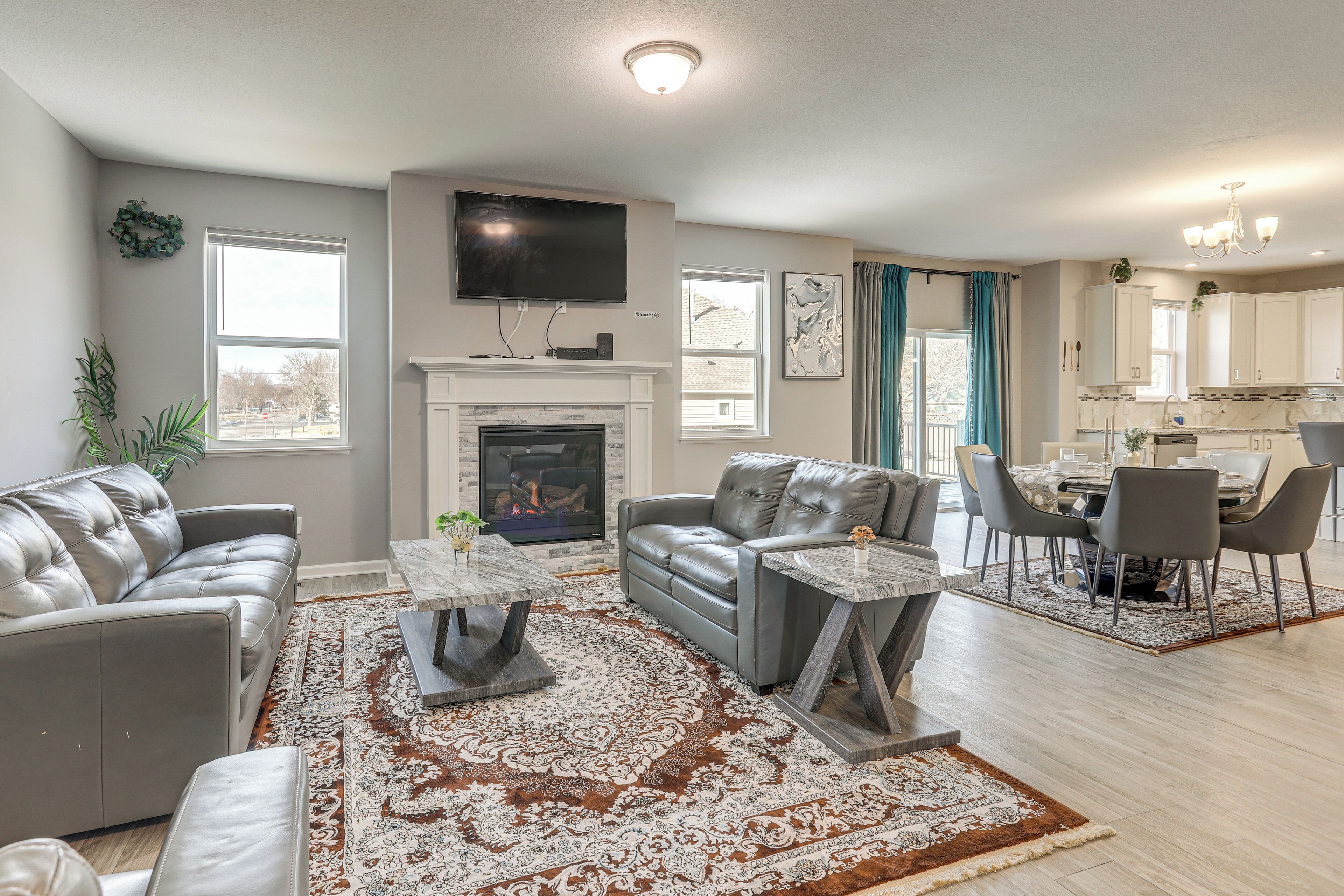 A modern living room with a fireplace, leather sofas, and a dining area with a chandelier.