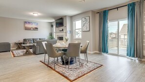 Uma sala de estar moderna com área de jantar, sofá cinza e um candelabro.