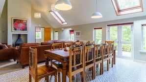 A spacious living room with a high ceiling, a dining area with wooden chairs and a table, and large windows allowing natural light. - The Coach House - UK35246 (Llanfyrnach)
