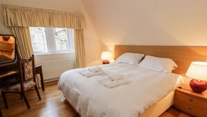 Une chambre bien rangée, avec un lit, des tables de chevet, un bureau et une chaise.