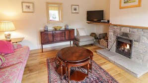 Un salon avec une cheminée, un canapé, un téléviseur et un meuble en bois.