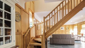 A wooden staircase leading to a living area with a sofa and a cabinet with glass doors. - 2 bedroom accommodation in Kirkmichael, near Ayr (Kirkmichael, near Ayr)