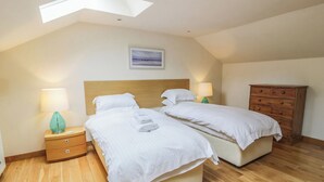A bedroom with two beds, wooden nightstands, a dresser, and a skylight. - 2 bedroom accommodation in Kirkmichael, near Ayr (Kirkmichael, near Ayr)