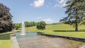 A stone patio with a fountain, surrounded by grass and trees. - 2 bedroom accommodation in Kirkmichael, near Ayr (Kirkmichael, near Ayr)