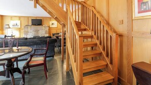 A wooden staircase leading to an upper floor, a living room with a sofa and a fireplace, and a dining area with a table and chairs. - Coach House - UK7236 (Kirkmichael, near Ayr)