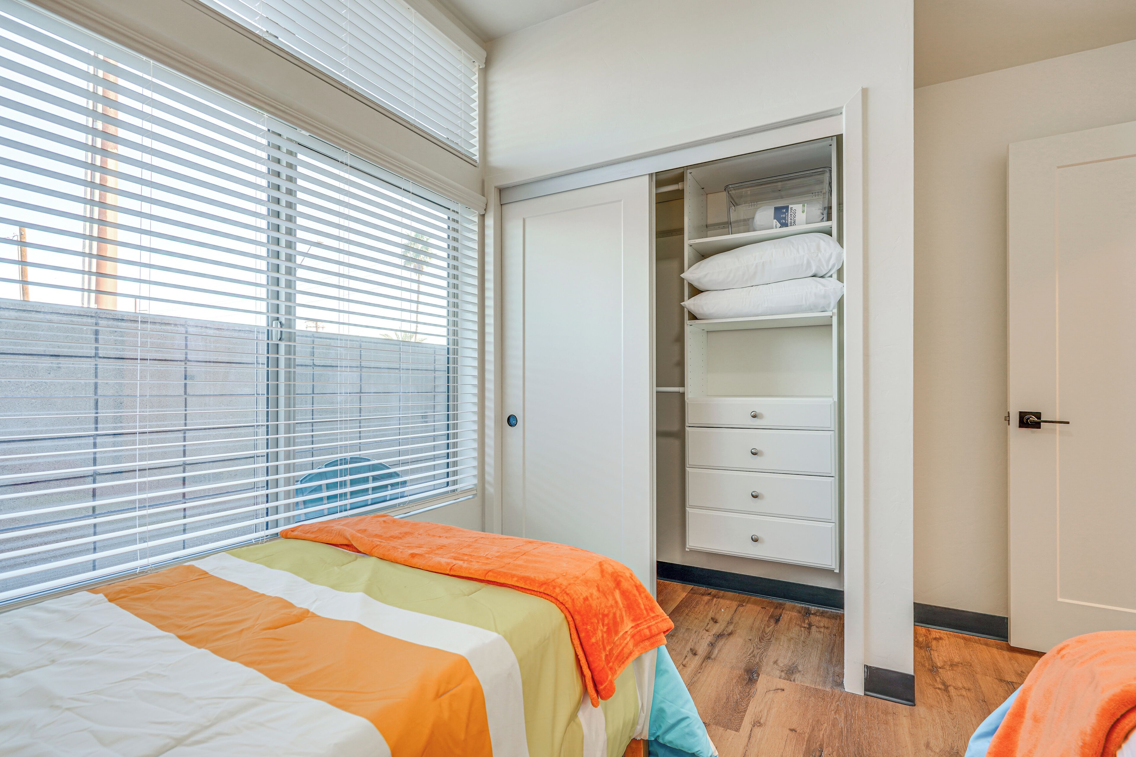 Une chambre à coucher avec un lit, une armoire et une fenêtre avec des stores.