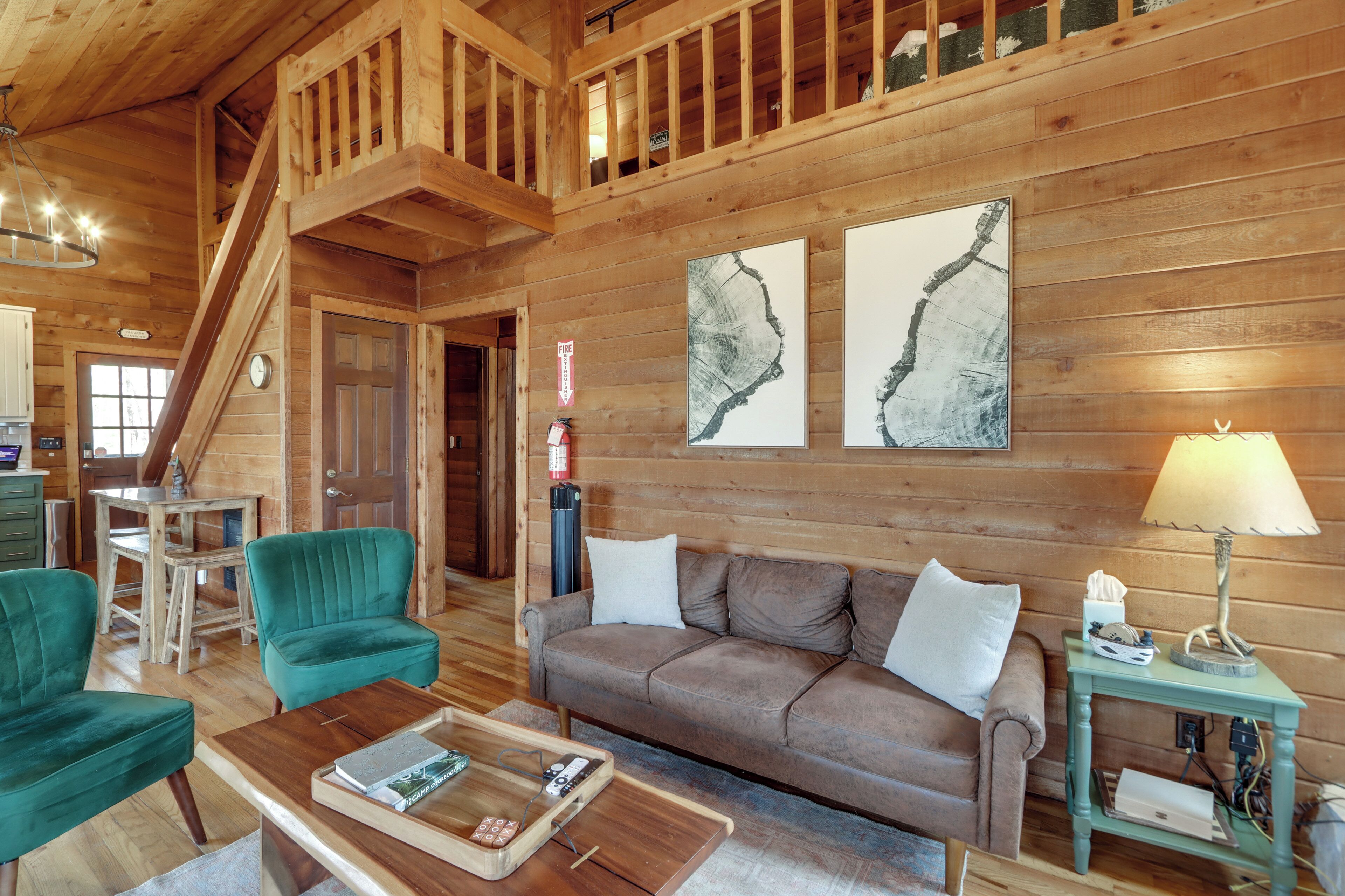 A wooden interior with a sofa, chairs, a coffee table, and artwork on the walls.