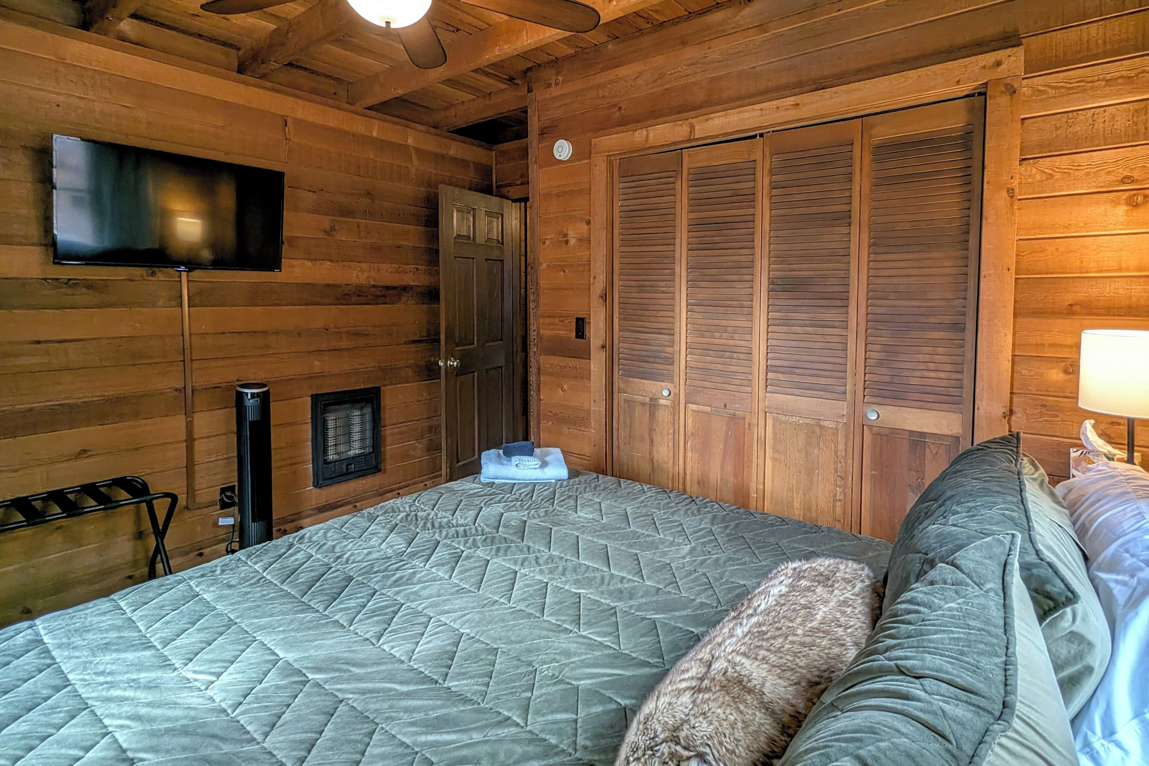 Ein Zimmer in einer Holzhütte mit einem Bett, einem an der Wand montierten Fernseher, einer Heizung und einem Kleiderschrank.