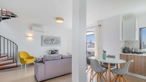 Un appartement moderne doté d’un espace de vie comprenant un canapé, une table à manger avec des chaises, une cuisine avec des placards et un escalier.