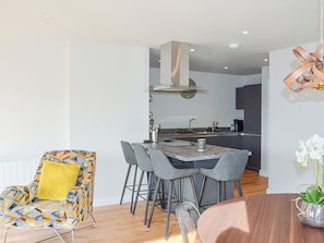 A modern kitchen with a central island, bar stools, and a dining table. - 2 bedroom accommodation in Skipton (Skipton)