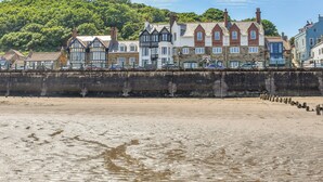 A coastal hotel with traditional architecture, a sandy beach, and a forested hill in the background. - 2 bedroom accommodation in Sandsend, near Whitby (Sandsend, near Whitby)