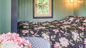Een slaapkamer met een bed, een raam en een wandlamp.