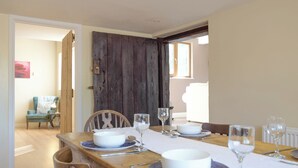 A dining area with a wooden table set for four, including bowls, wine glasses, and cutlery. - 3 bedroom accommodation in Portway (Portway)