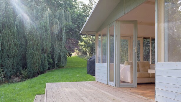 A wooden deck with a glass door leading to a room with a sofa and a covered table. - 3 bedroom accommodation in Portway (Portway)