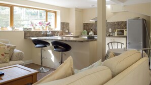 A modern kitchen with a central island, bar stools, a dining table, and a refrigerator. - 3 bedroom accommodation in Portway (Portway)