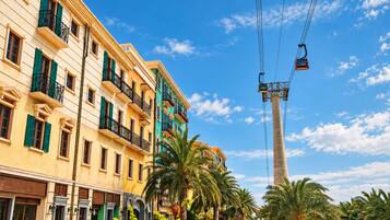 A multi-story building with balconies, a cable car system, and palm trees.