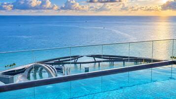Una piscina infinita con vista despejada al océano y una estructura tipo puente.