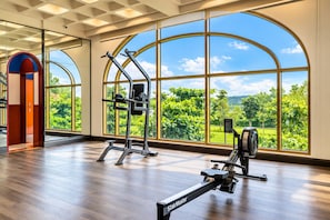 Un gimnasio amplio con ventanas grandes que ofrecen vistas a zonas verdes y un cielo despejado.