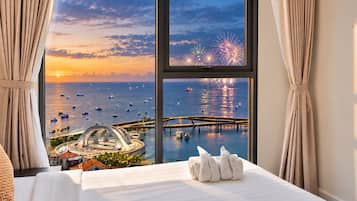 A hotel room with a large window overlooking a marina, a bridge, and fireworks.