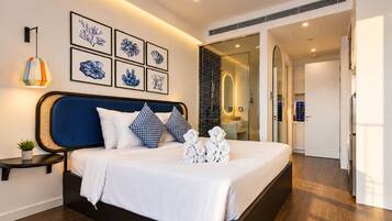 Una habitación de hotel moderna con una cama grande, una mesita de noche con lámpara y una pared decorada con obras enmarcadas.
