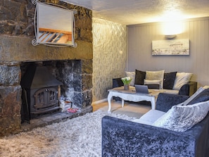 A cozy living room with a stone fireplace, a sofa set, a coffee table, and a painting on the wall. - 3 bedroom accommodation in Tremadog (Tremadog)