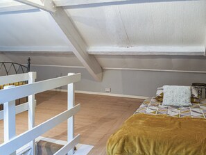 A room with a sloped ceiling, a bed with a patterned bedspread, and a white railing. - 3 bedroom accommodation in Tremadog (Tremadog)