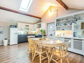 A kitchen with a dining table, chairs, a refrigerator, and a shelf with decorative items. - 2 bedroom accommodation in Greenhalgh (Greenhalgh)