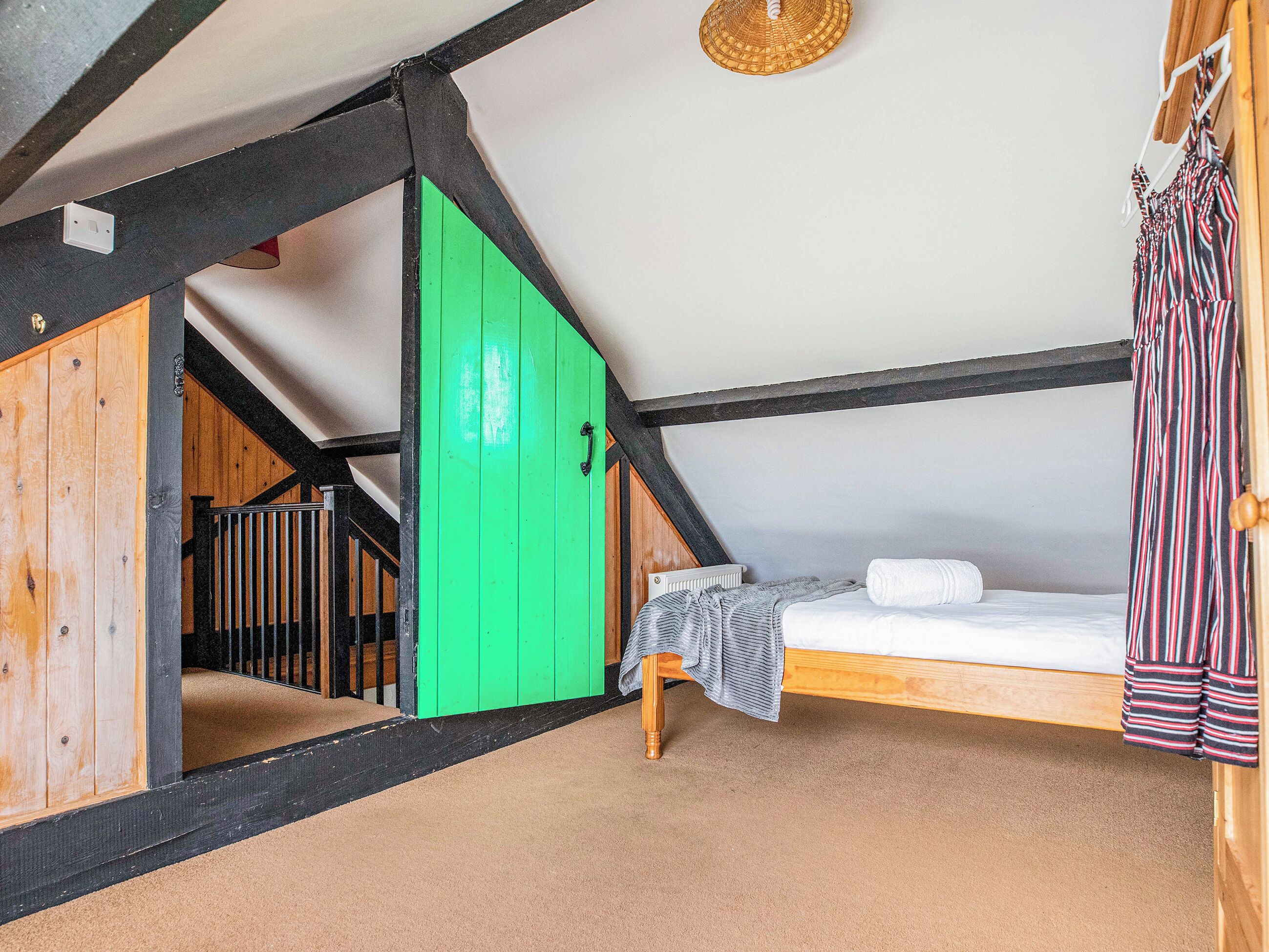 Ein Schlafzimmer im Loft-Stil mit einer grünen Tür, einem Einzelbett und einer Holztreppe.