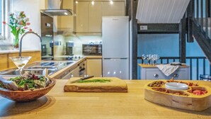 A kitchen with a wooden table, a cutting board, a bowl of salad, and a meat dish. - 3 bedroom accommodation in Crackington Haven (Crackington Haven)