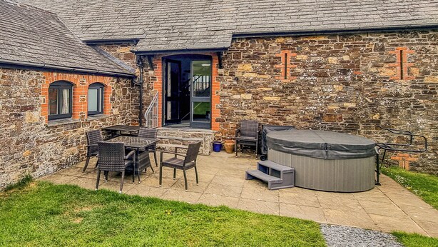 A stone building with a tiled roof, a patio with outdoor furniture, and a hot tub. - 3 bedroom accommodation in Crackington Haven (Crackington Haven)